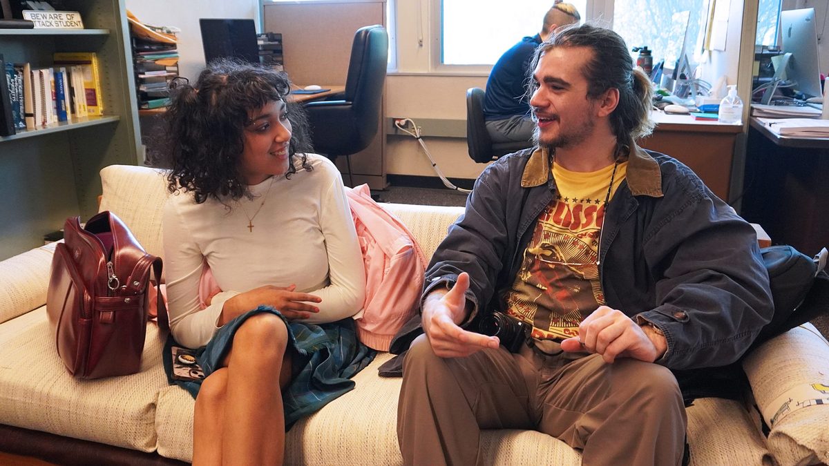 Students talking to each other sitting on a couch.