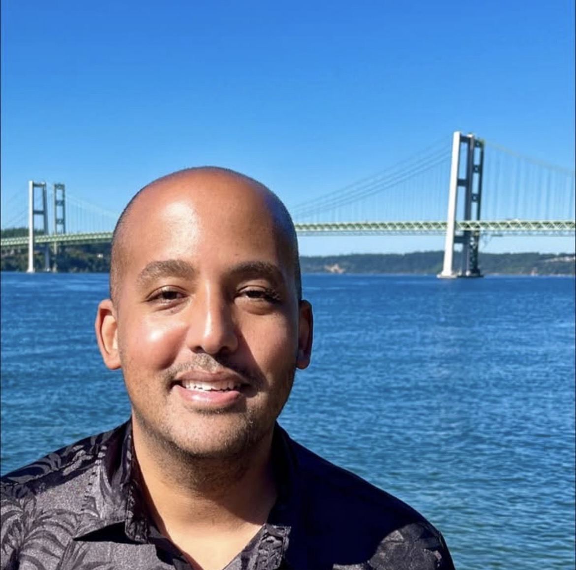 image of man in front of water and bridge